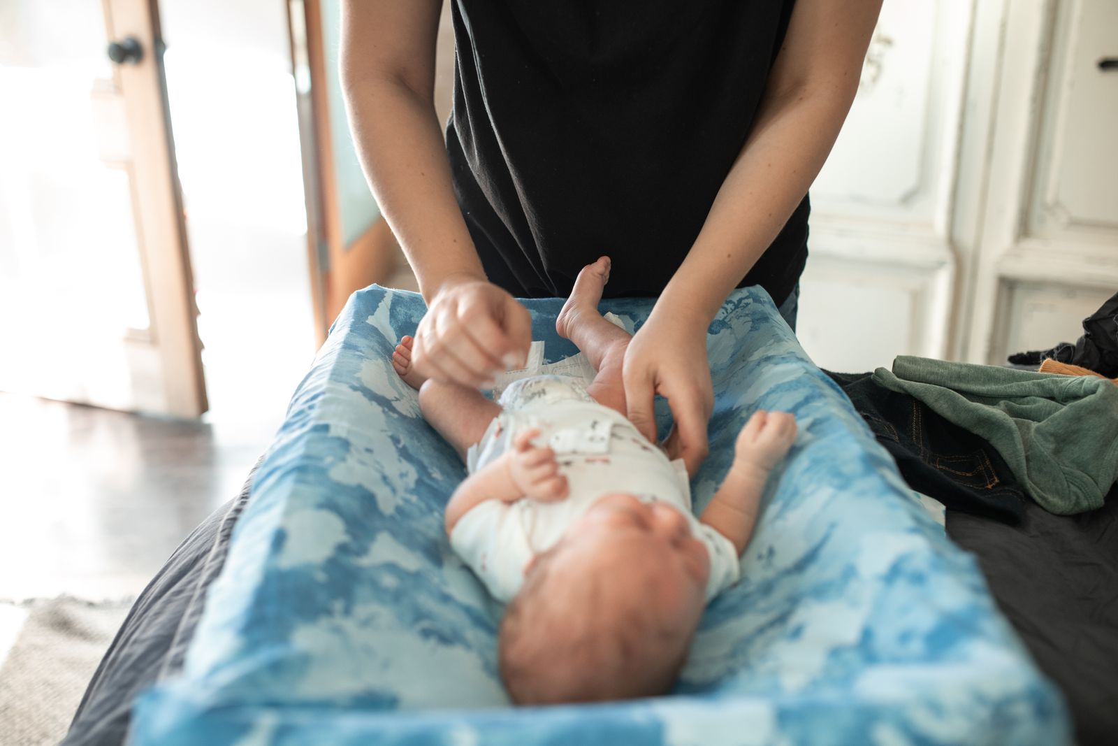 Baby lying on a changing pad during a diaper change, legs relaxed