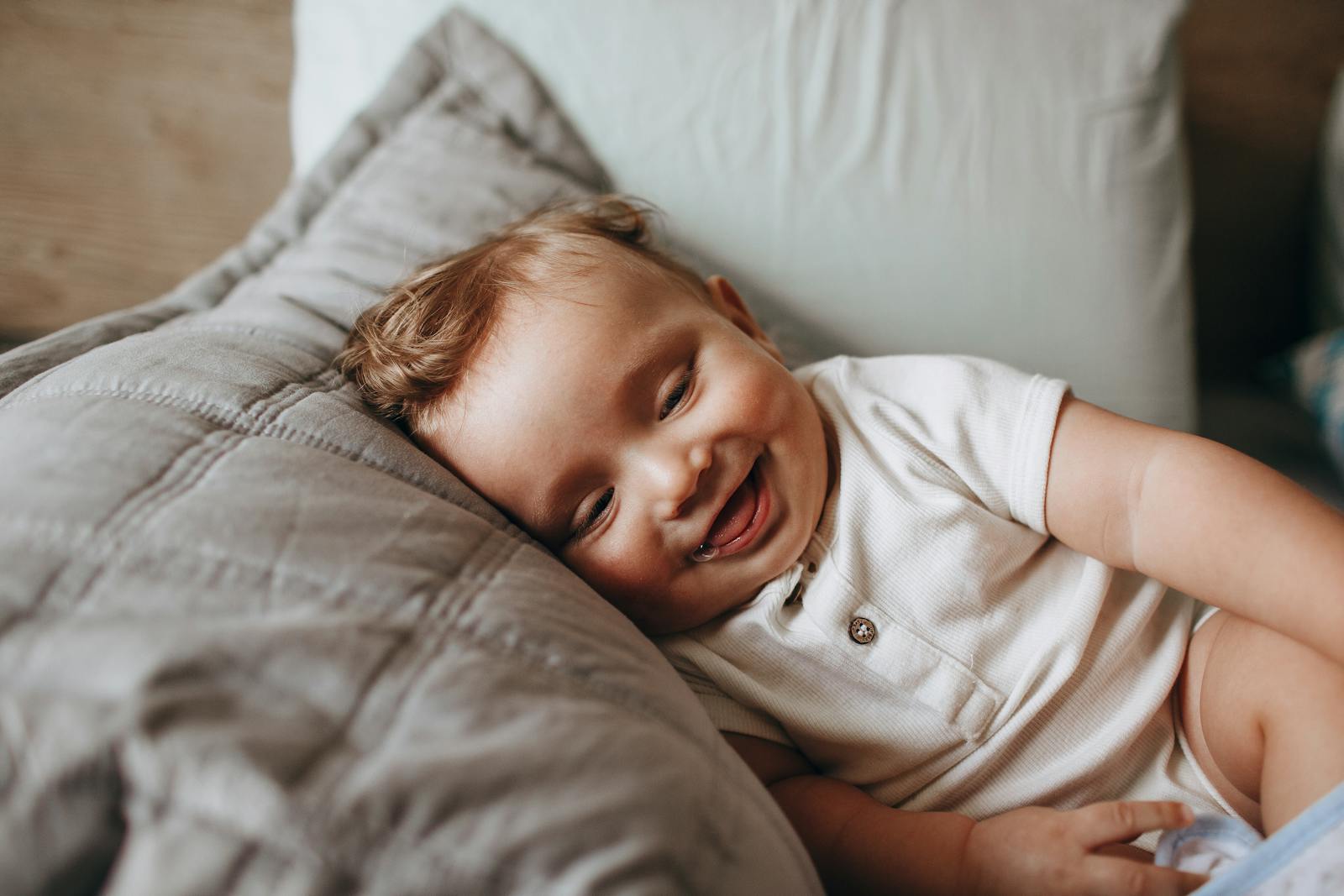 A thriving baby lies on a pillow smiling, a sign of good milk intake