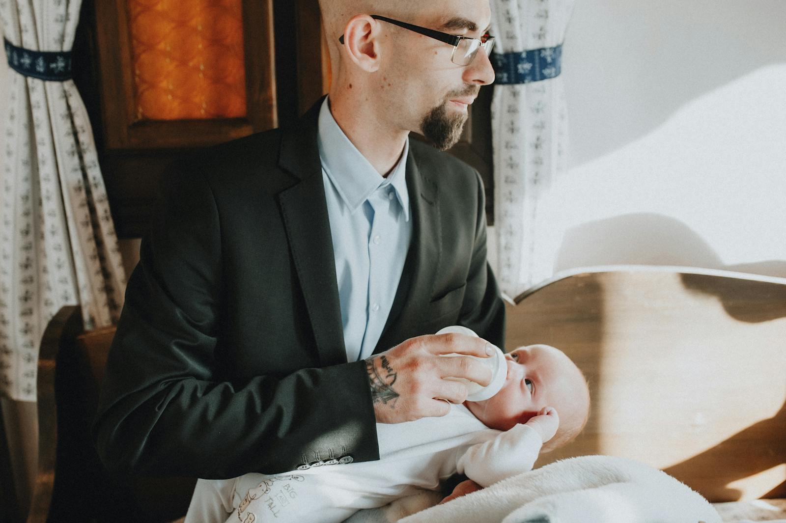 Parents on a bed feeding their baby with a wide-base bottle