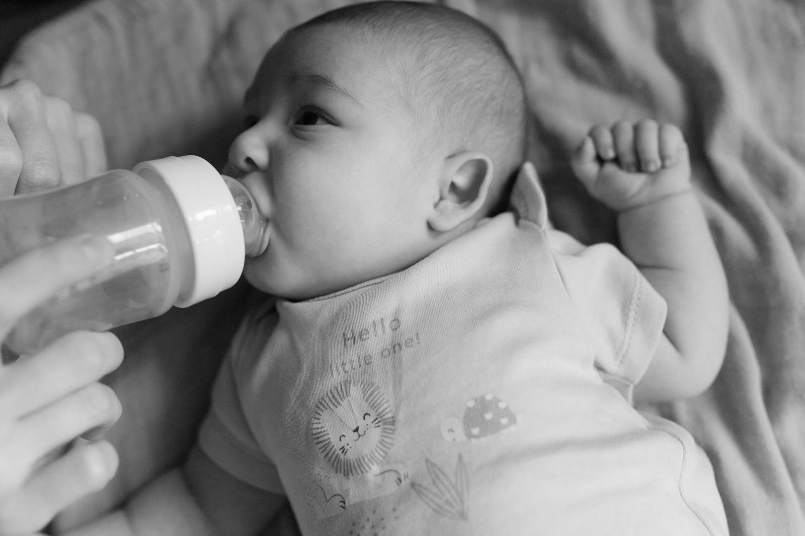 A baby being fed gently from a bottle, hand visible