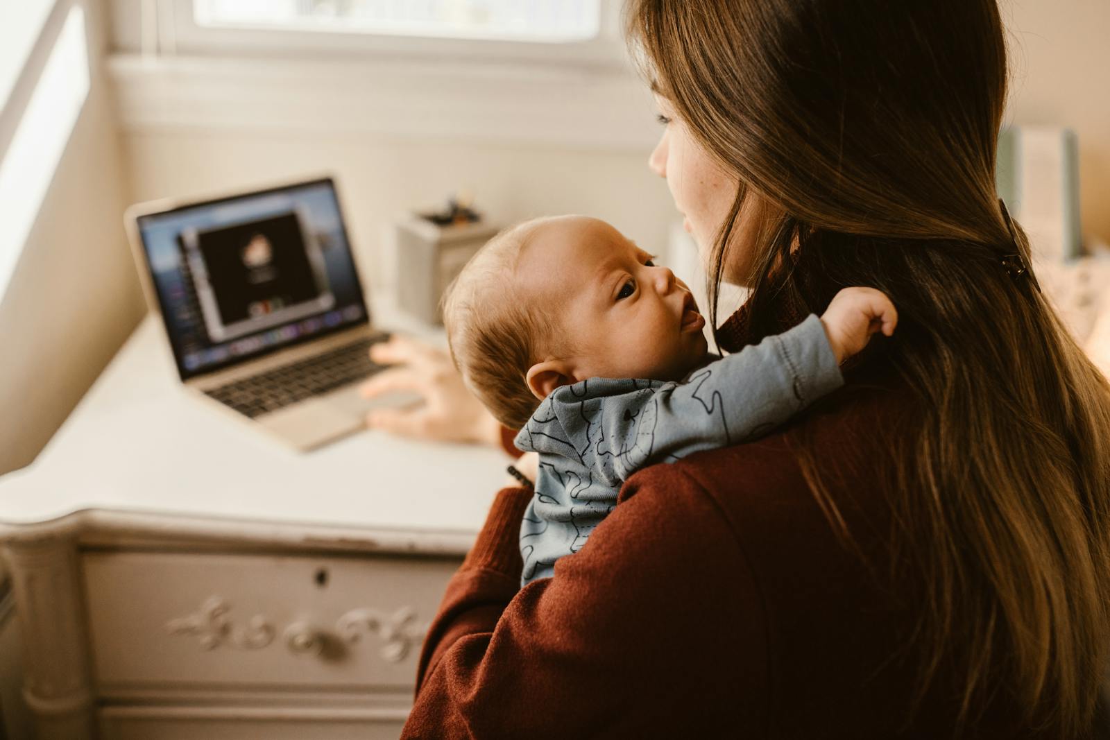 Mom multitasking at desk with laptop and baby