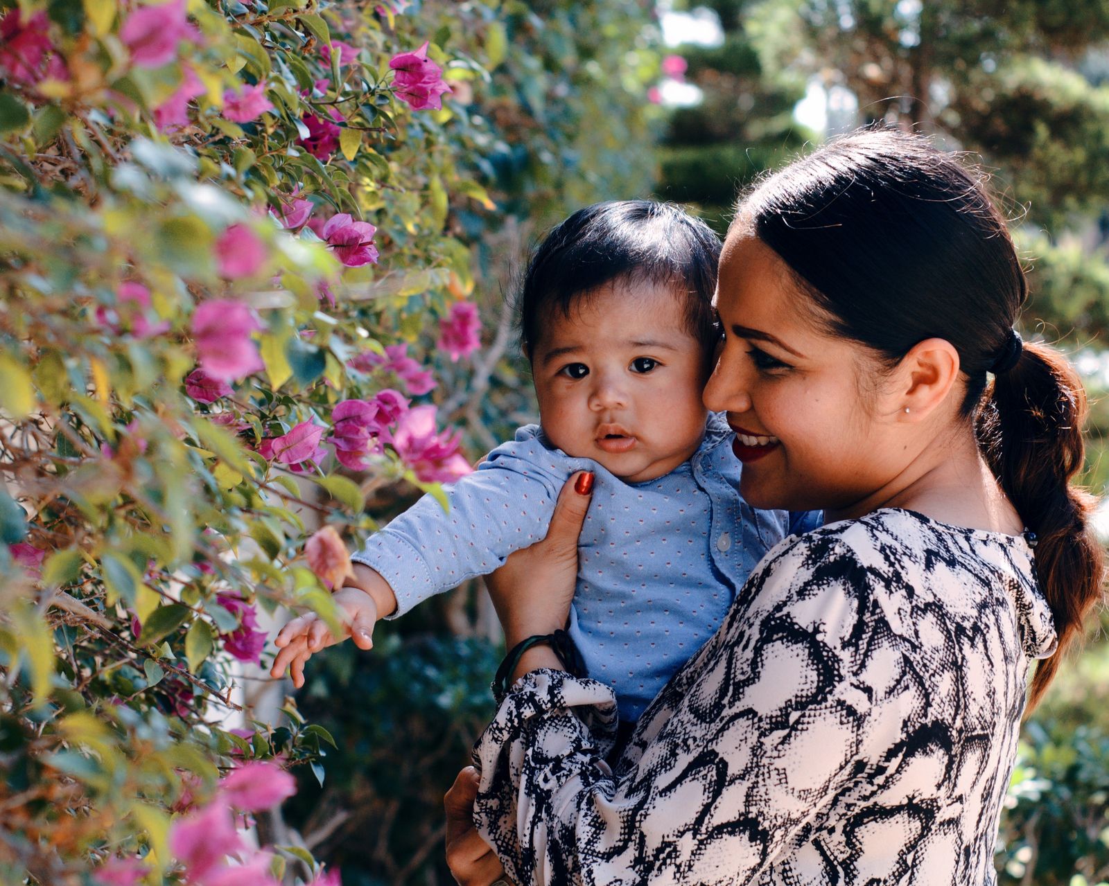 A mother holding her calm baby near flowers, both relaxed