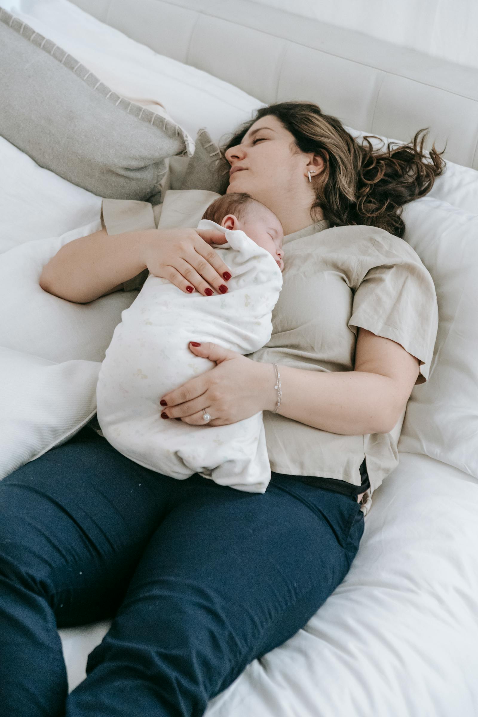 Mother lying on her side in bed, holding newborn close to her chest for a nighttime feed