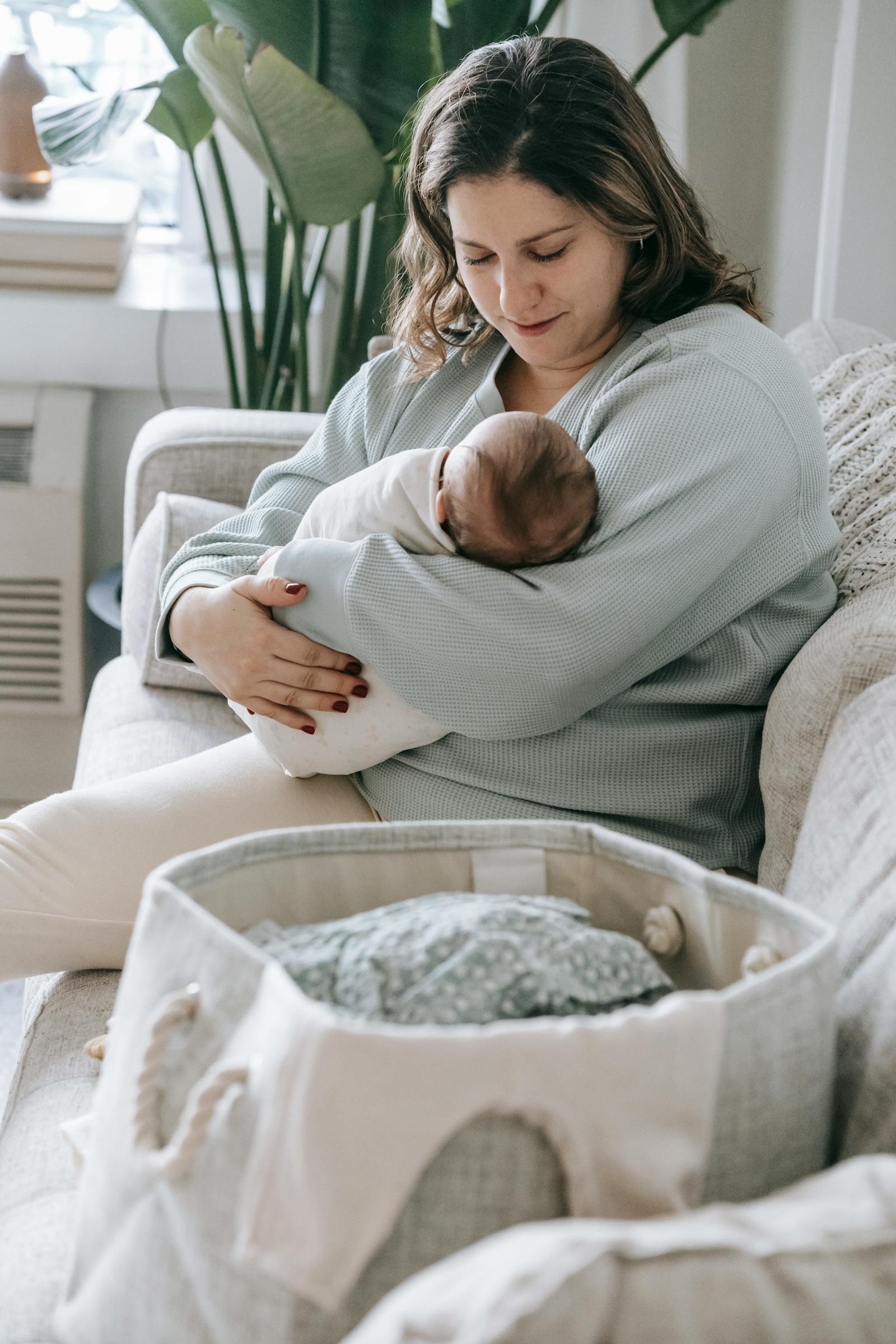 Mother in a cozy living room nursing her newborn on a couch