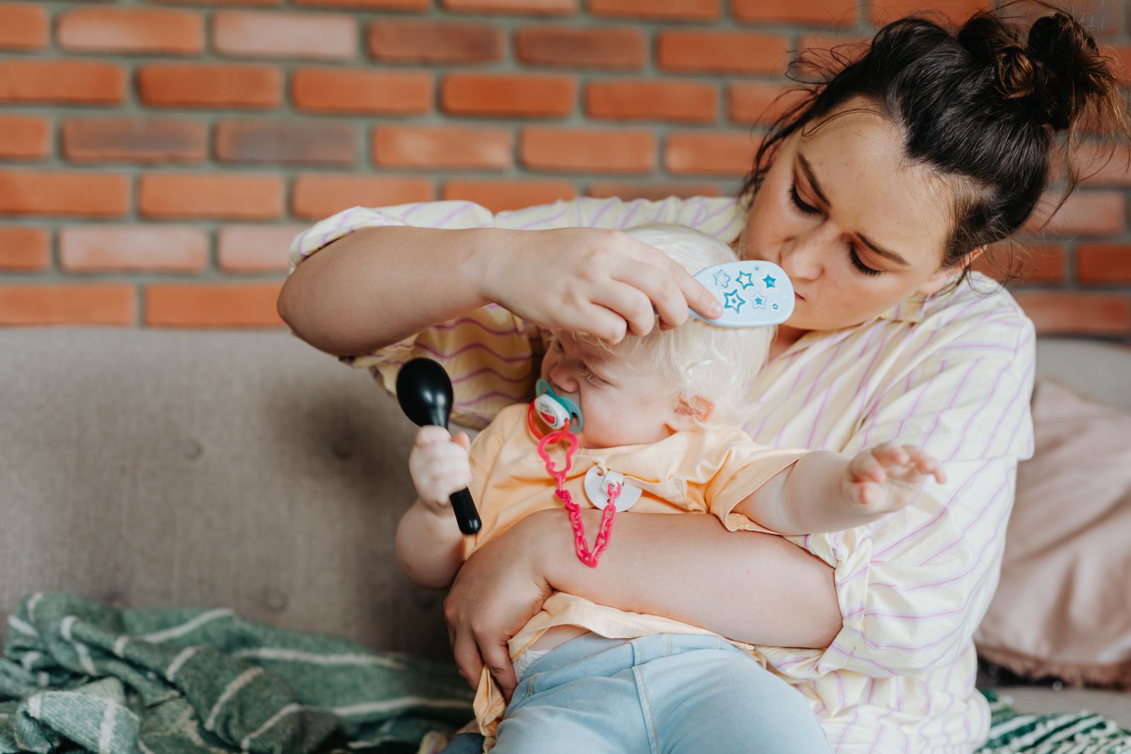 A parent gently brushing a baby's hair and scalp while holding them close