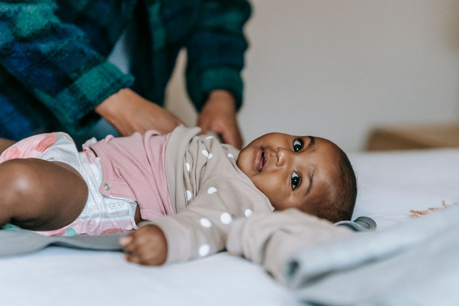 Smiling baby lying on a bed in just a diaper