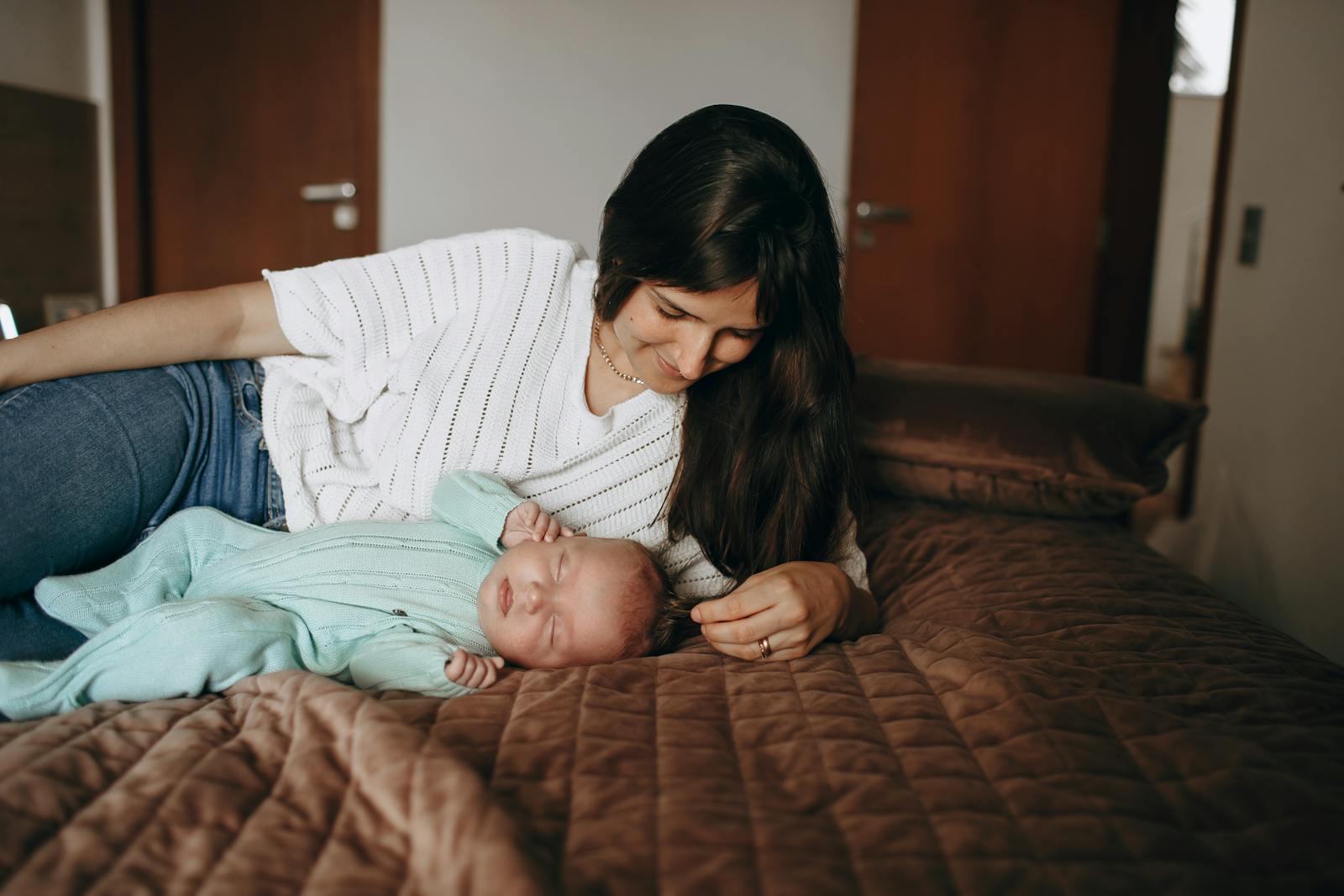 Mom in nursing top holding sleeping newborn cozy at home