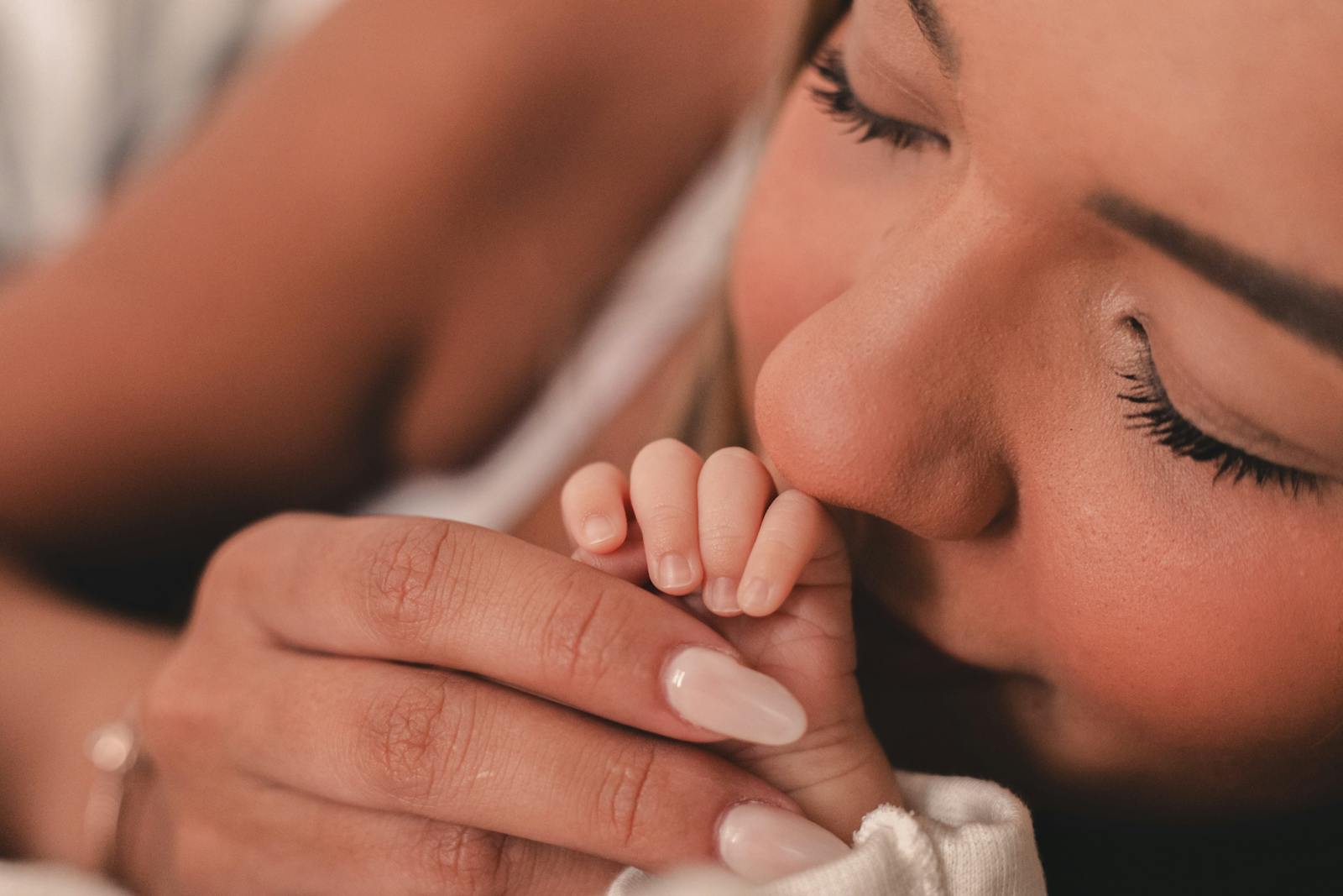Mom kissing baby's tiny hand, soft tender close-up