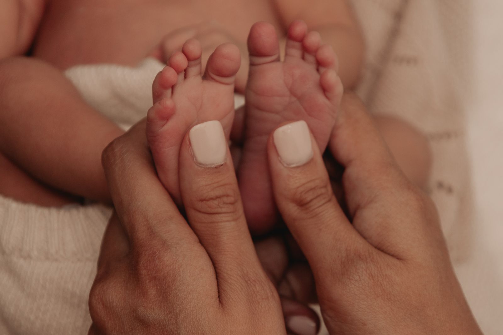 A parent's hands cradling a newborn's feet