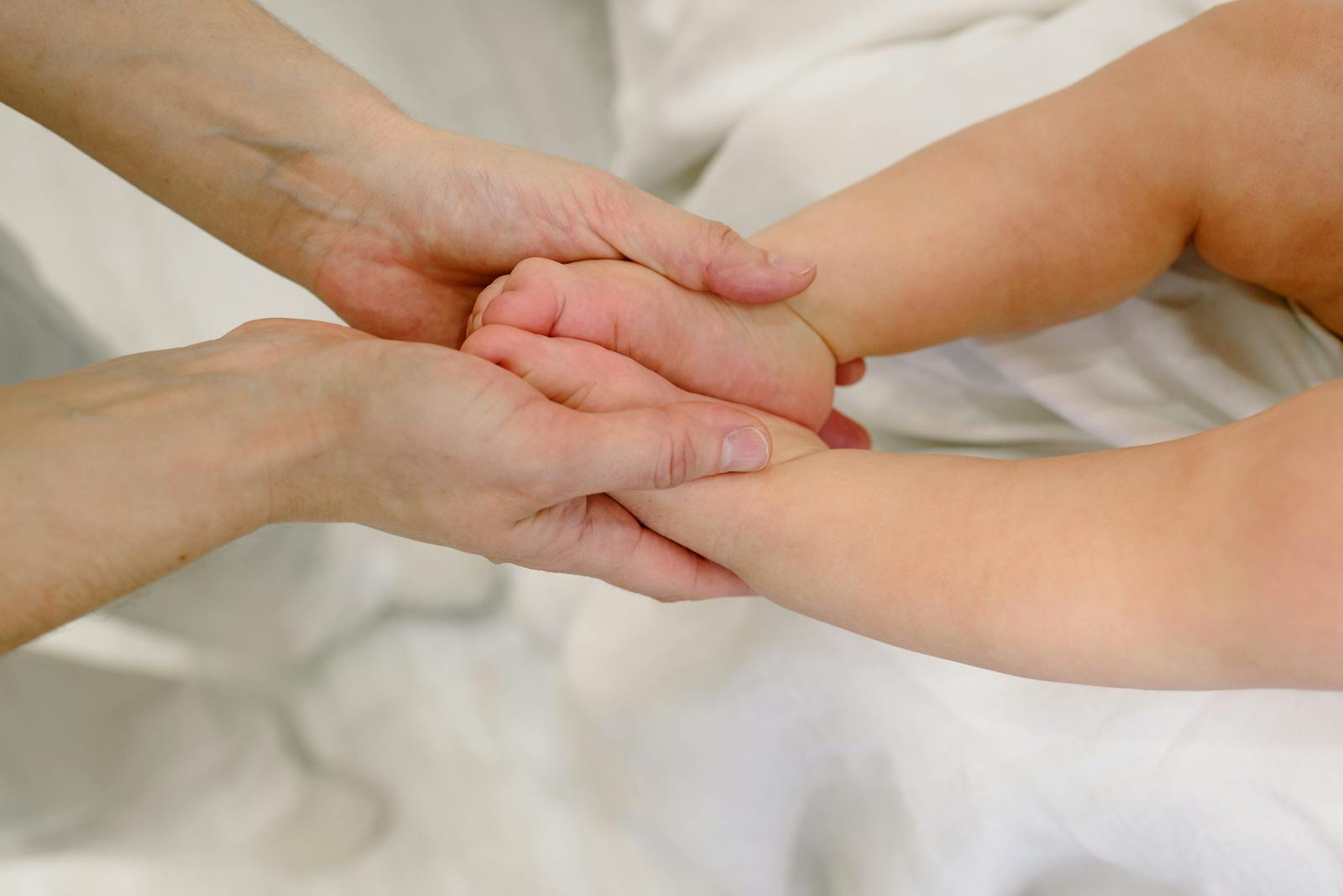 Adult hands gently holding a baby's foot during a calming routine