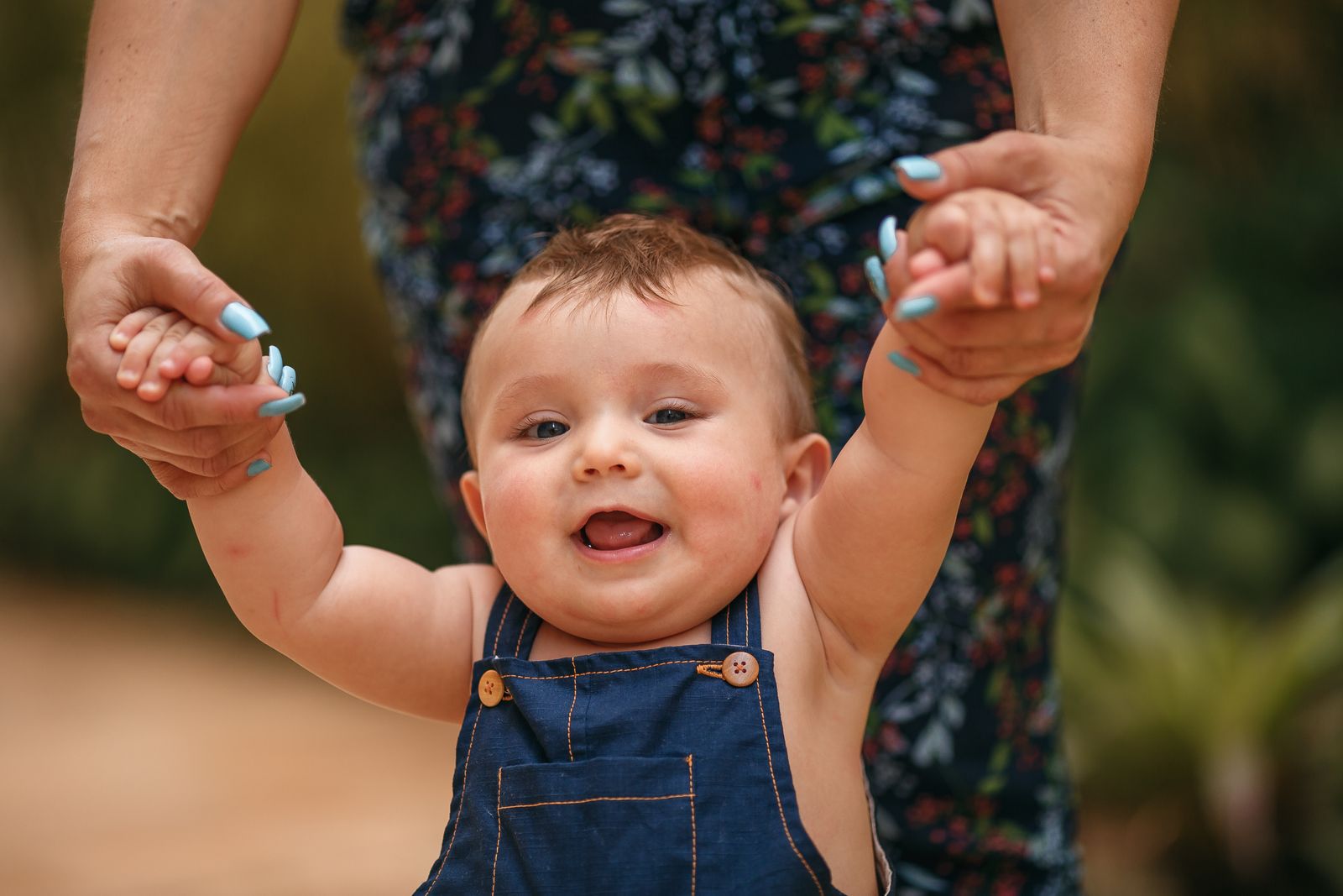 A close-up of a baby smiling with the first bottom tooth just visible, cheeks pink and healthy